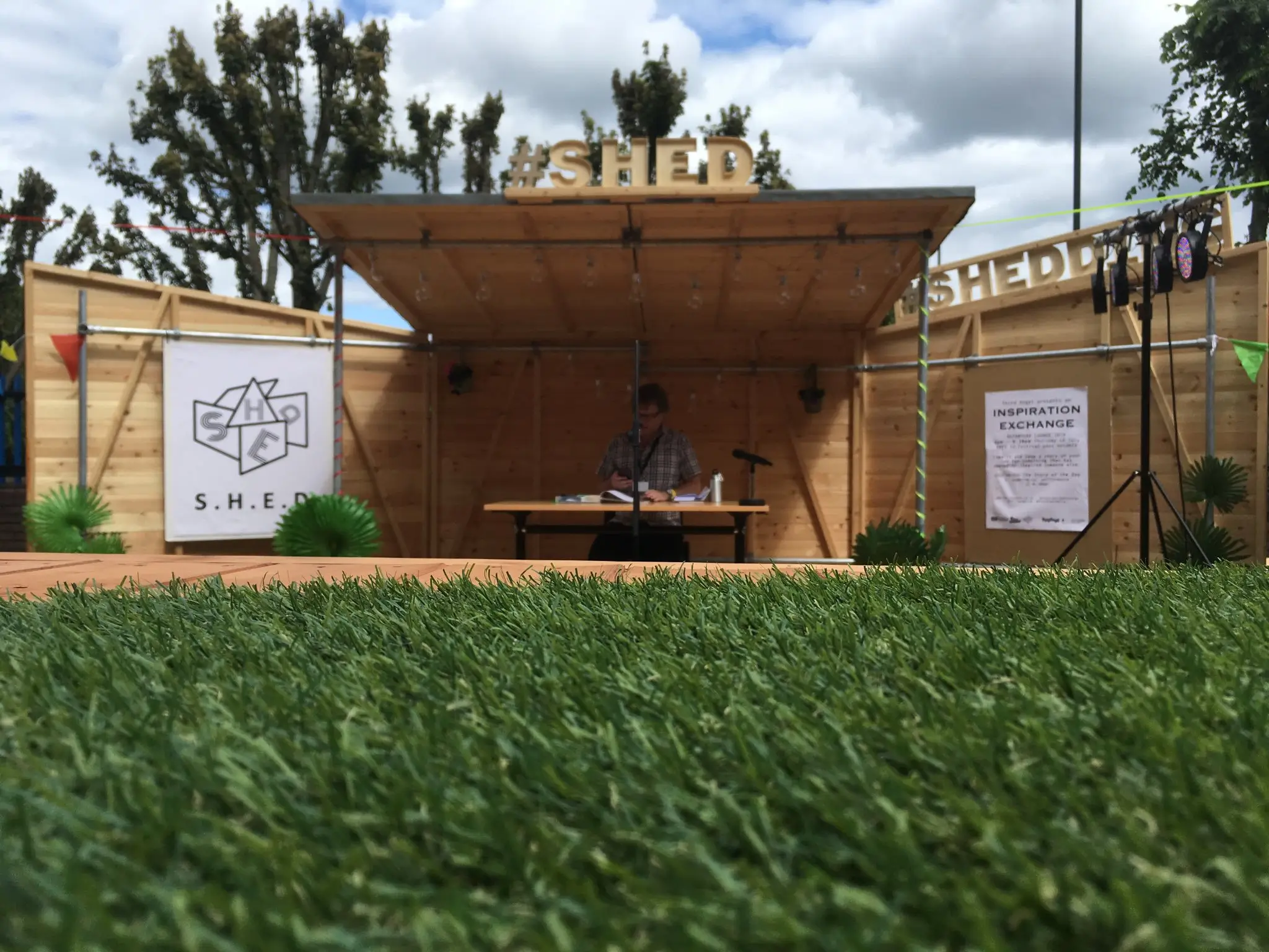 A man sitting at a desk in front of a wooden structure.
